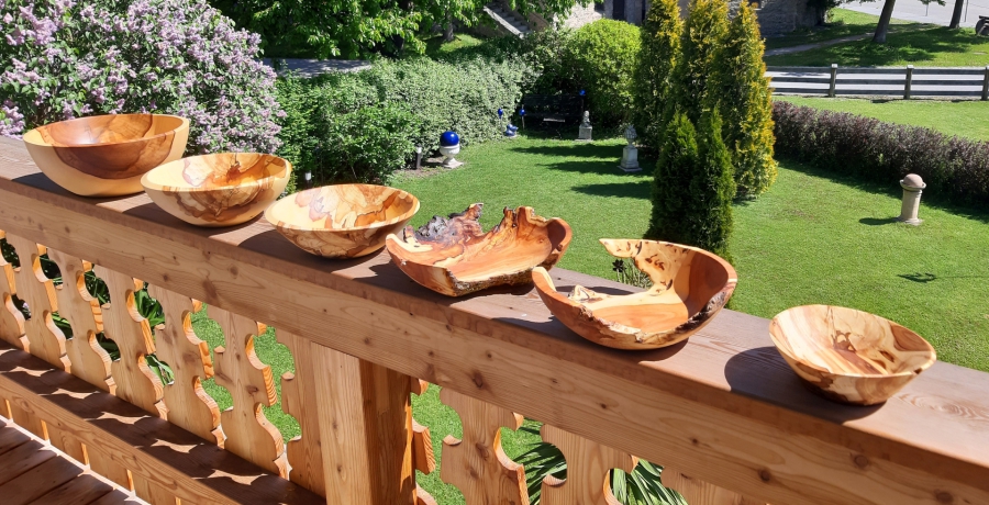 Sieben gedrechselte Holzschalen aus verschiedenen Hölzern auf einem Holzgeländer