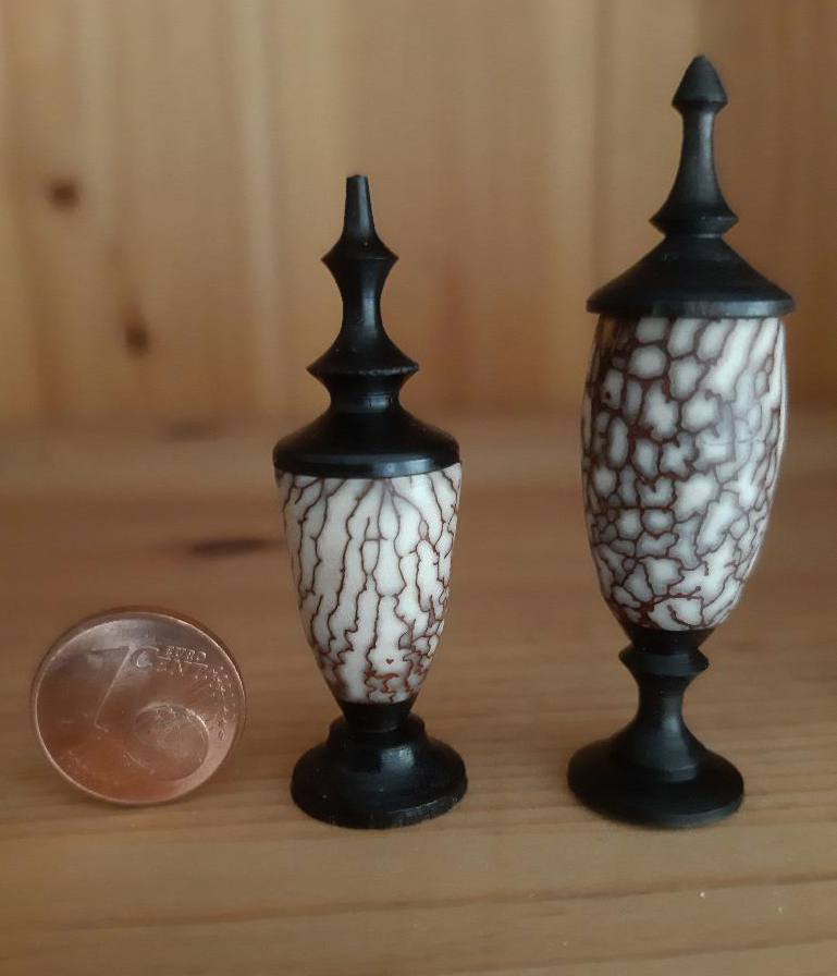 Links eine gedrechselte Betelnuss mit Fuß und Deckel aus Grenadillholz, rechts eine gedrechselte Palmnuss mit Grenadill-Fuß und einem Deckel aus Tagua-Nuss